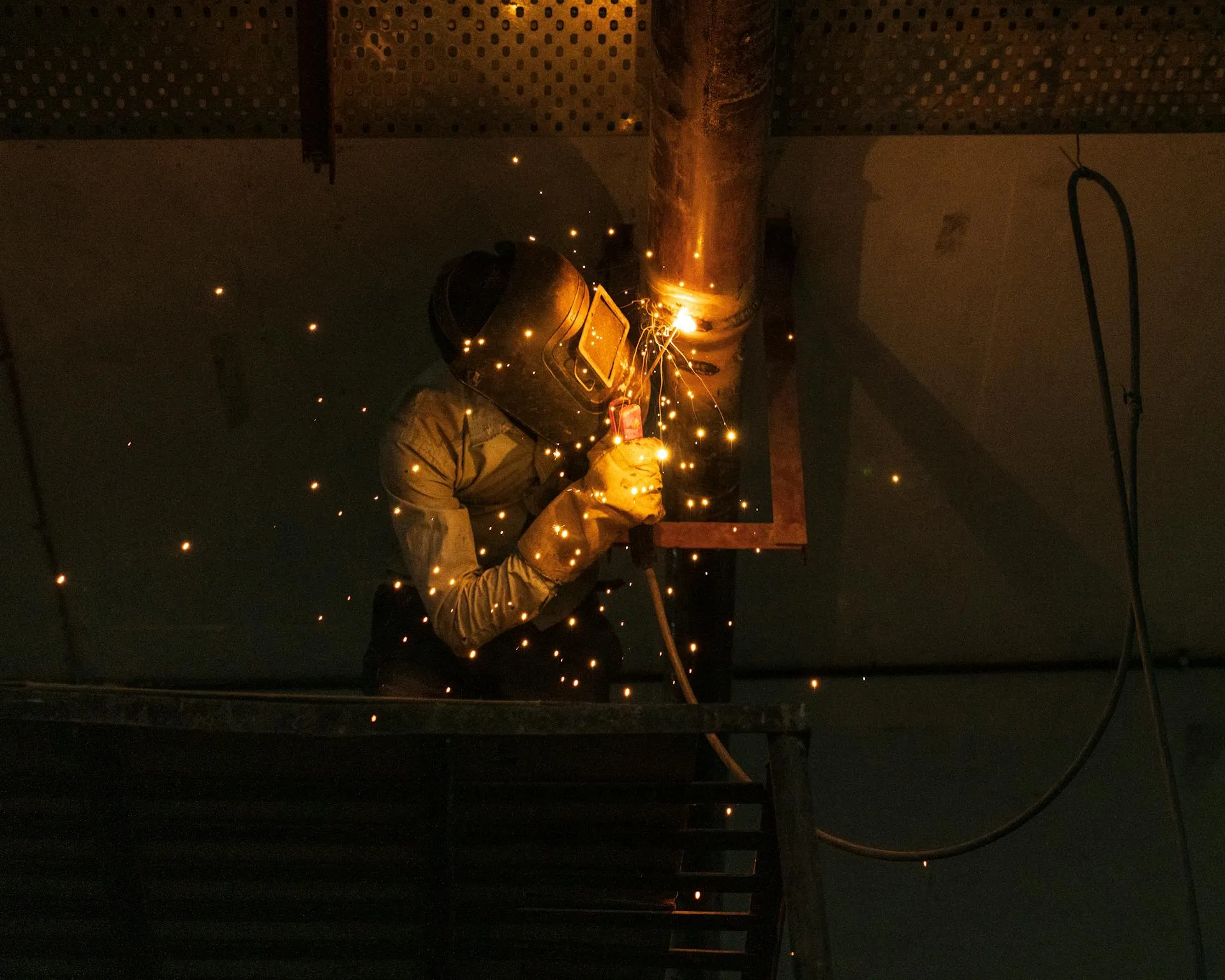 Soldador trabajando en tuberías de planta de tratamiento de agua industrial